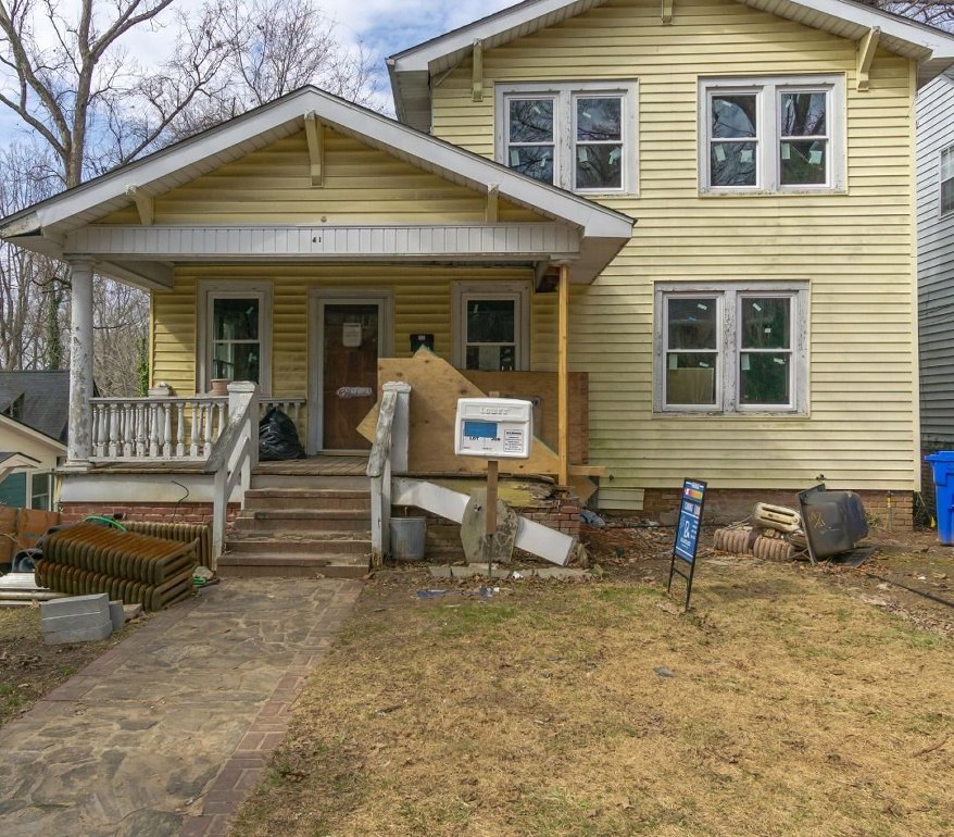 Craftsman house before: faded yellow siding, a boarded-up porch and debris in the yard