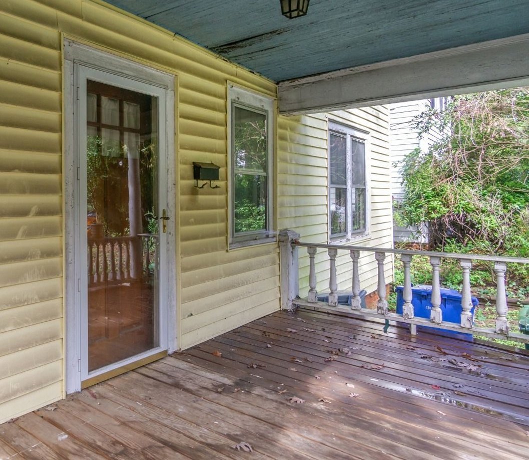 Front porch before: yellow siding, worn deck boards and a weathered ceiling