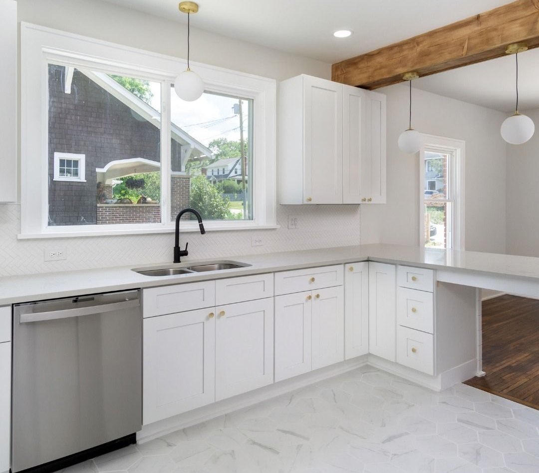 Kitchen after: white shaker cabinets, quartz counters and a wood ceiling beam