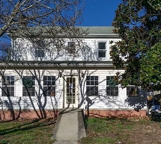 Two-story house before: white siding and an overgrown yard