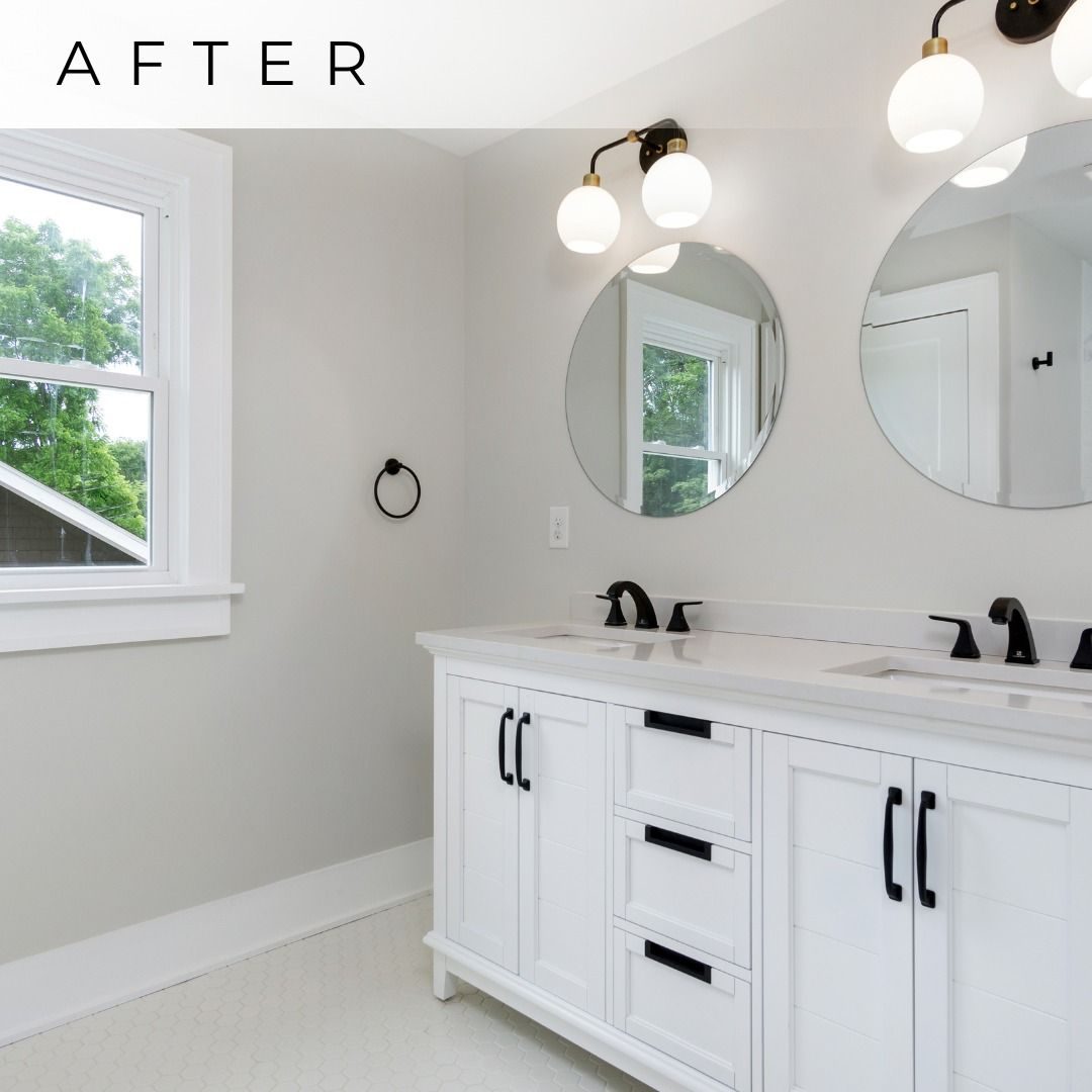 Remodeled bathroom with a white double vanity, black fixtures and round mirrors