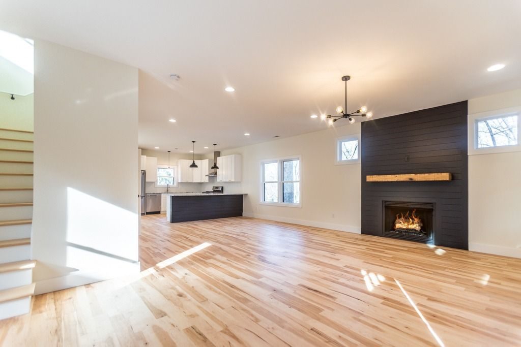 Open living area with hardwood floors and a dark fireplace surround