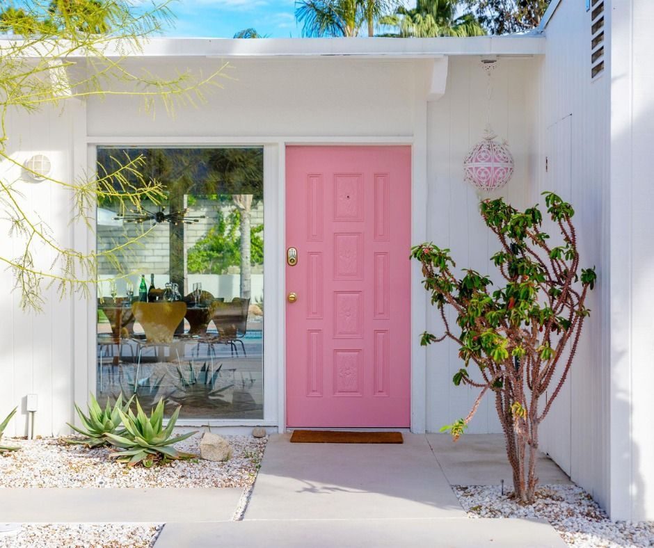 White exterior with a pink front door and glass sliding doors