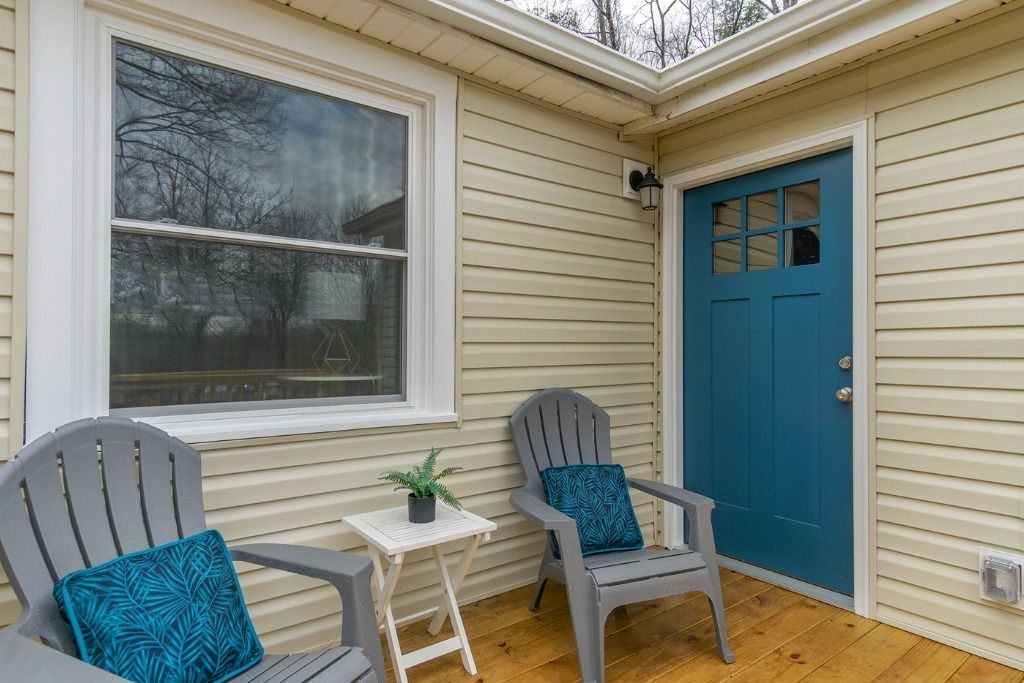 Porch with Adirondack chairs beside a blue door