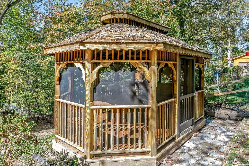 Screened wooden gazebo at the end of a stone path