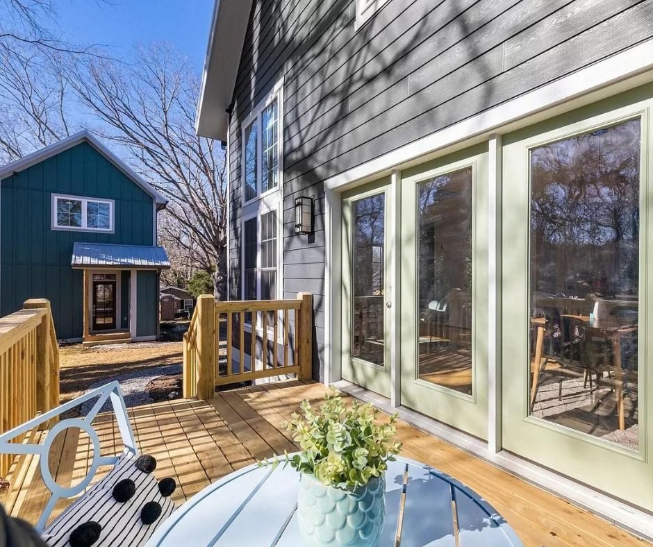 Wood deck along a dark-sided house with large windows