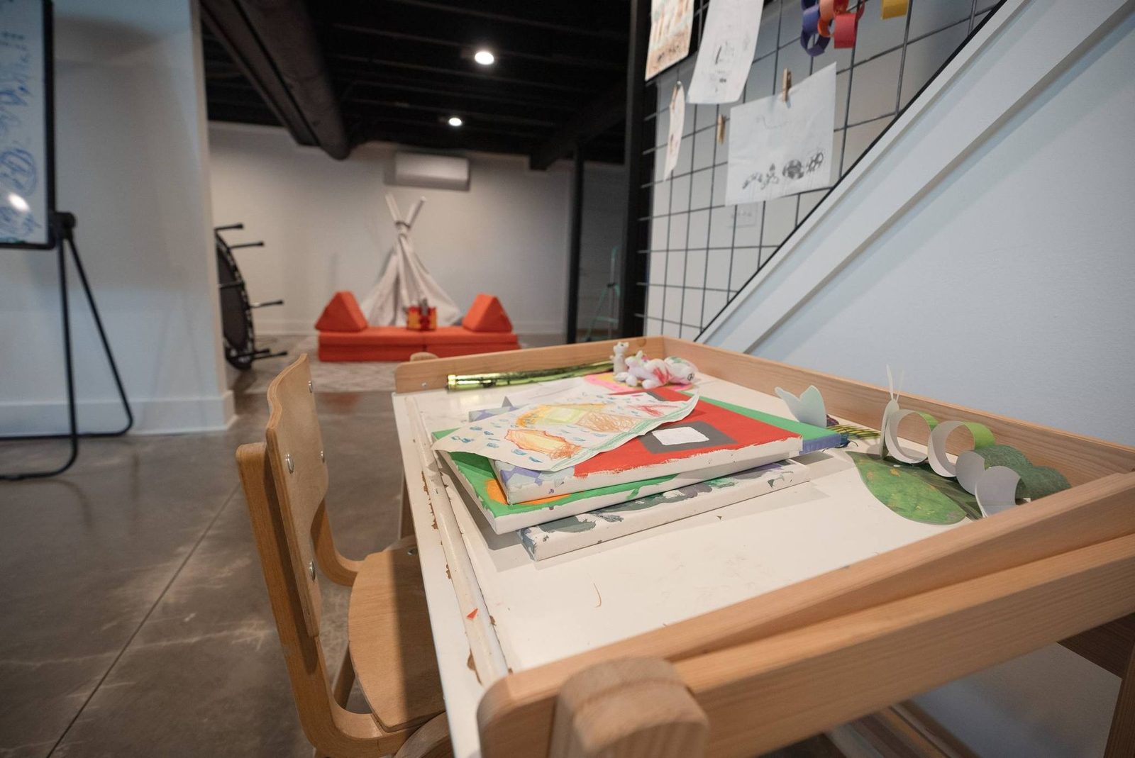 Finished basement with a craft table, a teepee and a concrete floor