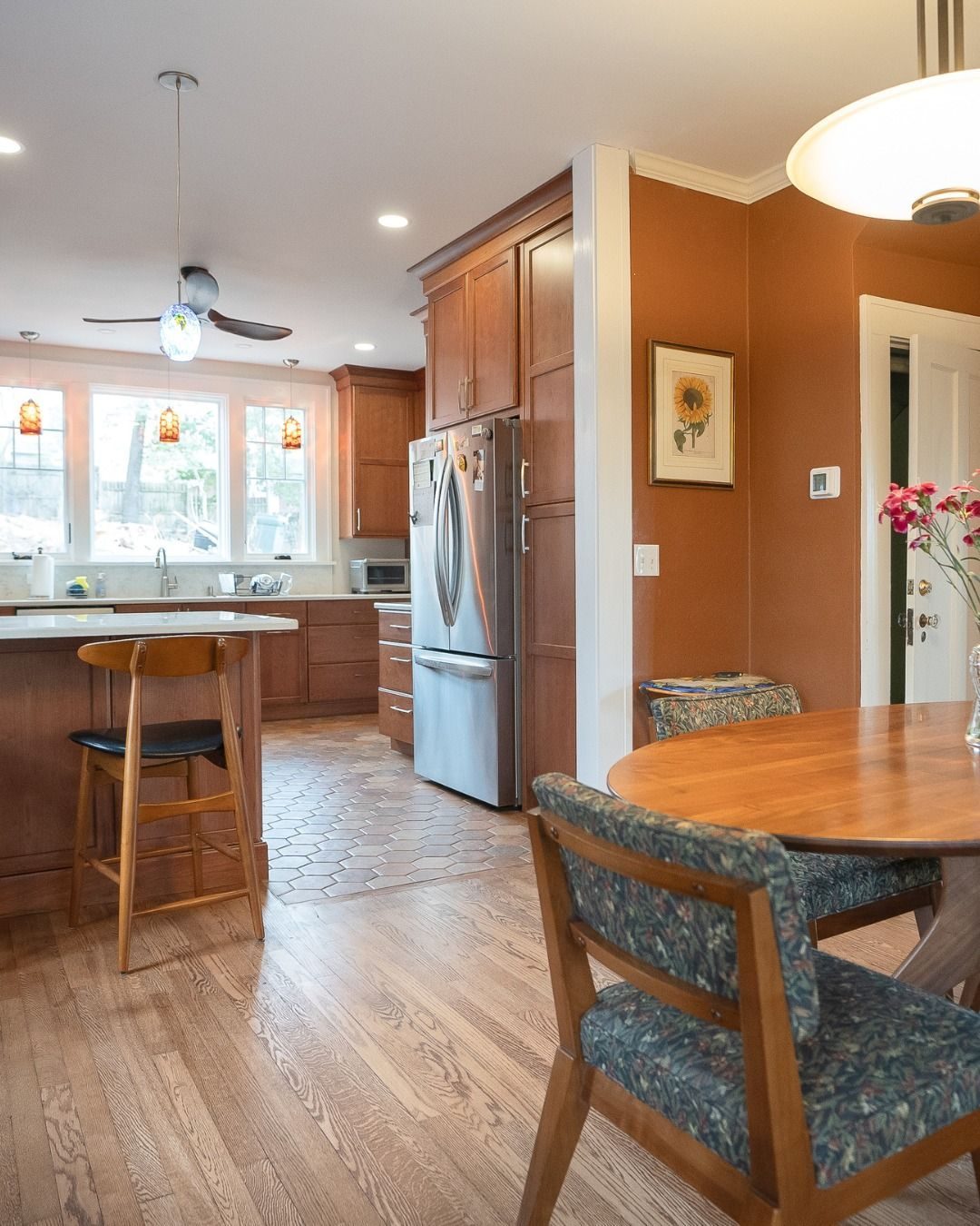 Kitchen with warm wood cabinets and a breakfast bar, seen from the dining table