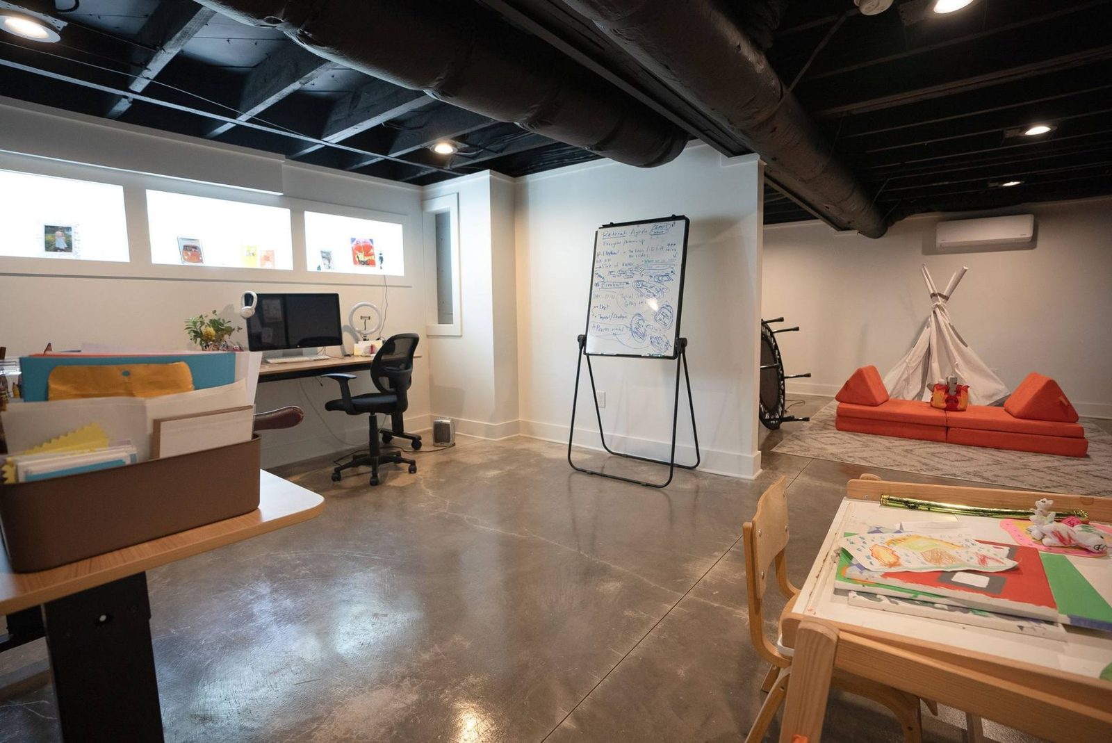 Lower-level studio with desks, a whiteboard and a sofa