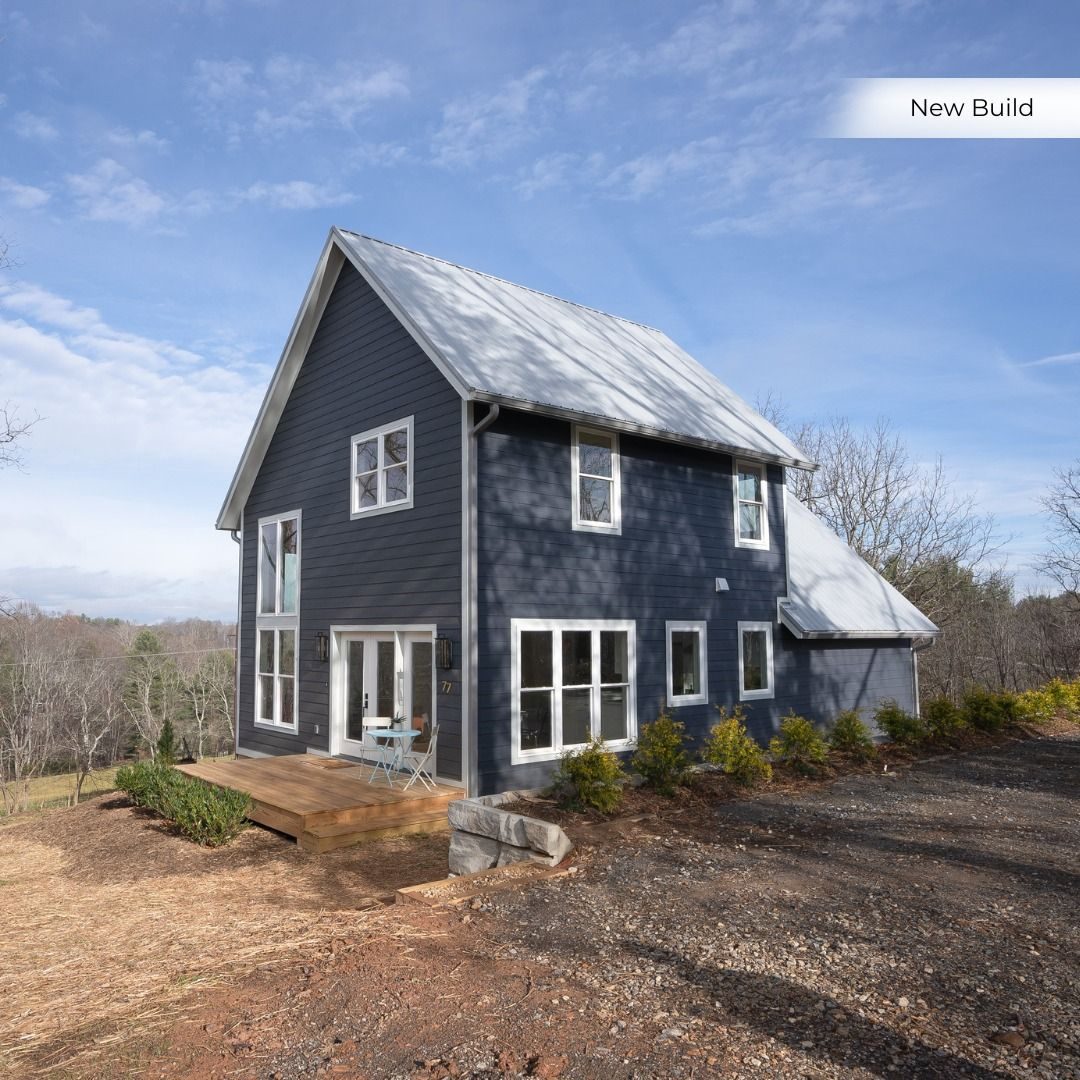Dark blue two-story new build with a metal roof on a hillside lot